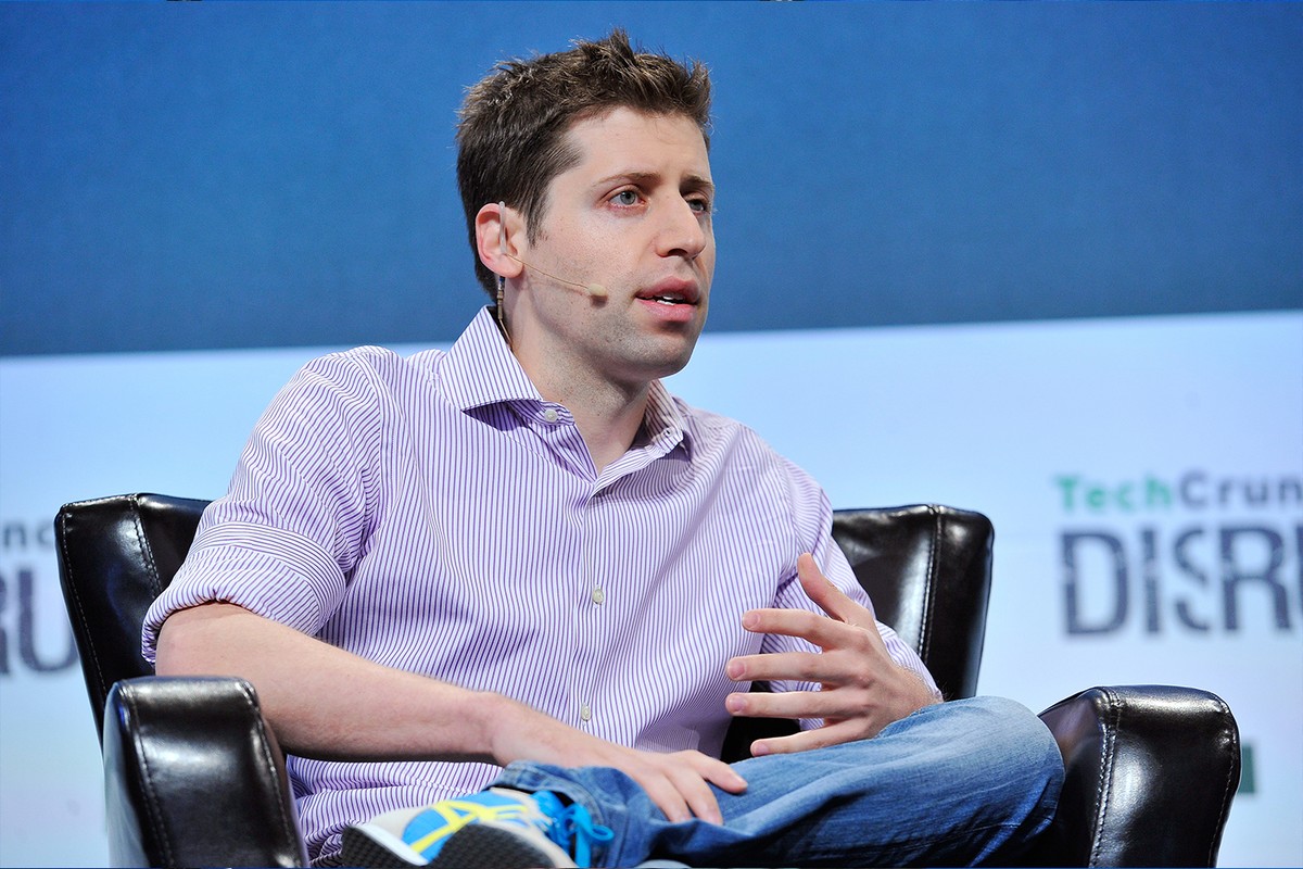 Sam Altman sits in a chair onstage at TechCrunch.