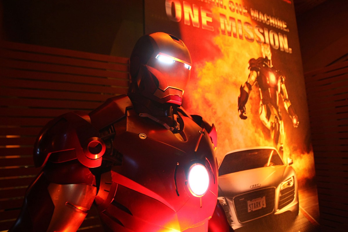 Figure in a red full body armor, superhero movie premiere, red lighting.